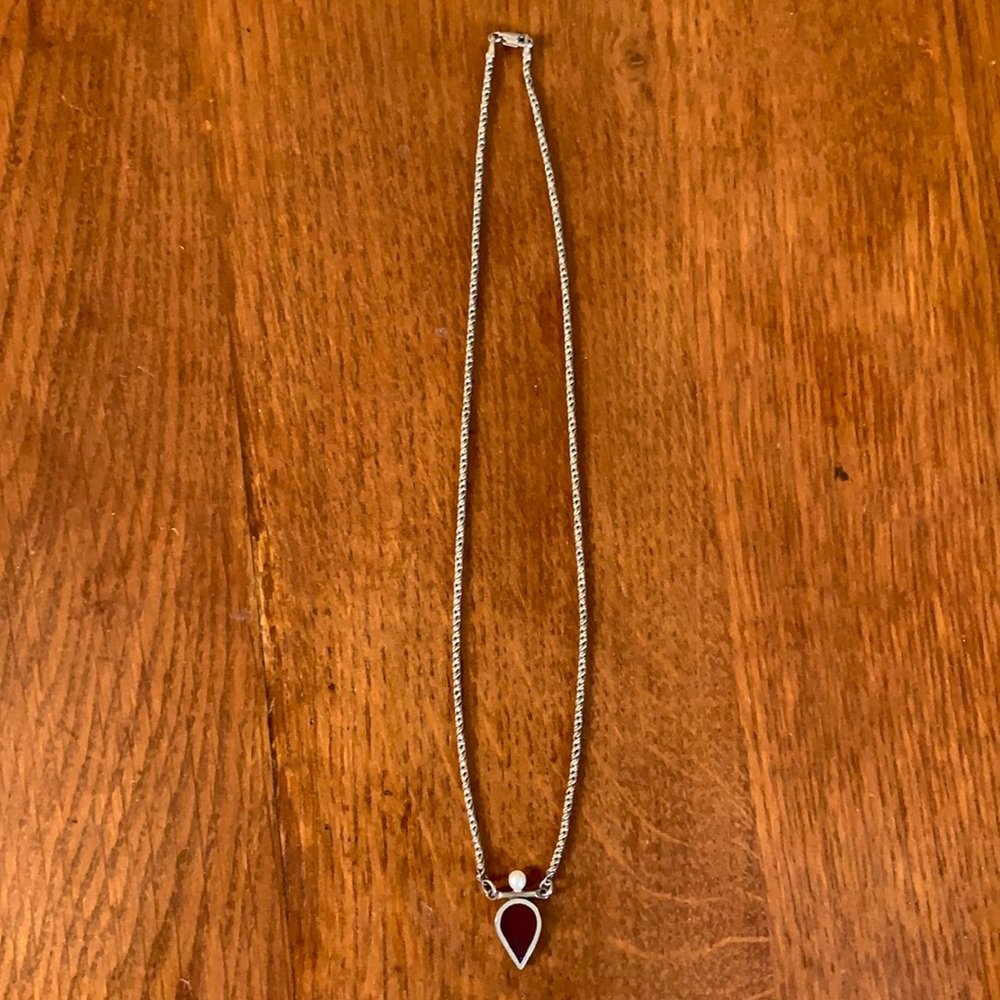 Silver necklace with teardrop pendant, pearl accent on top.